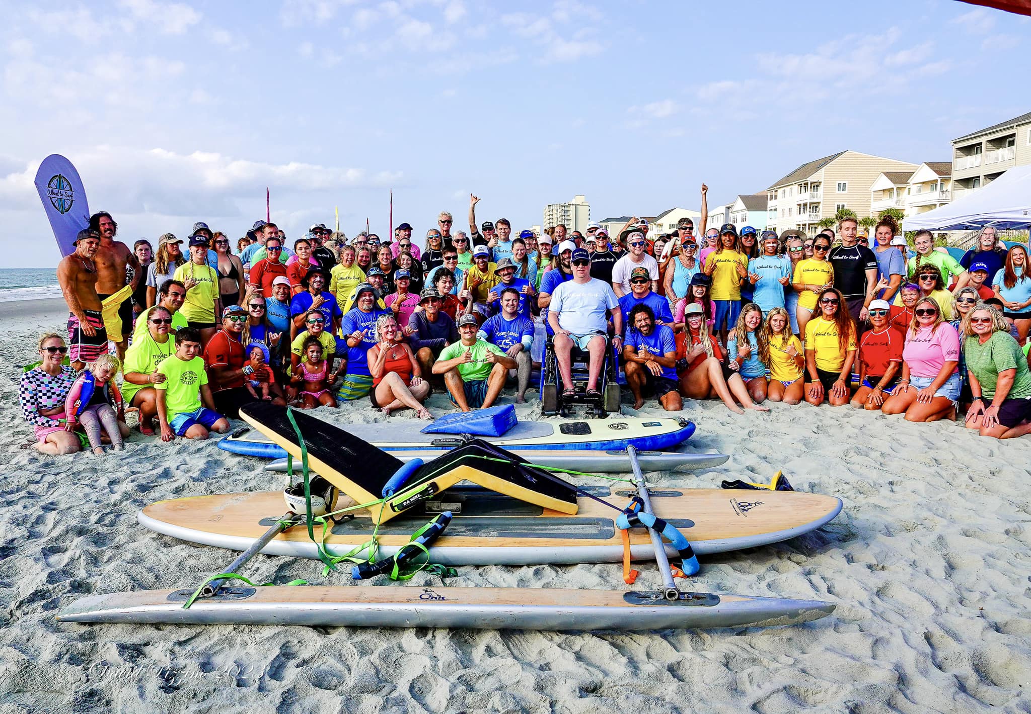 A group picture on the beach of a Wheel to Surf event