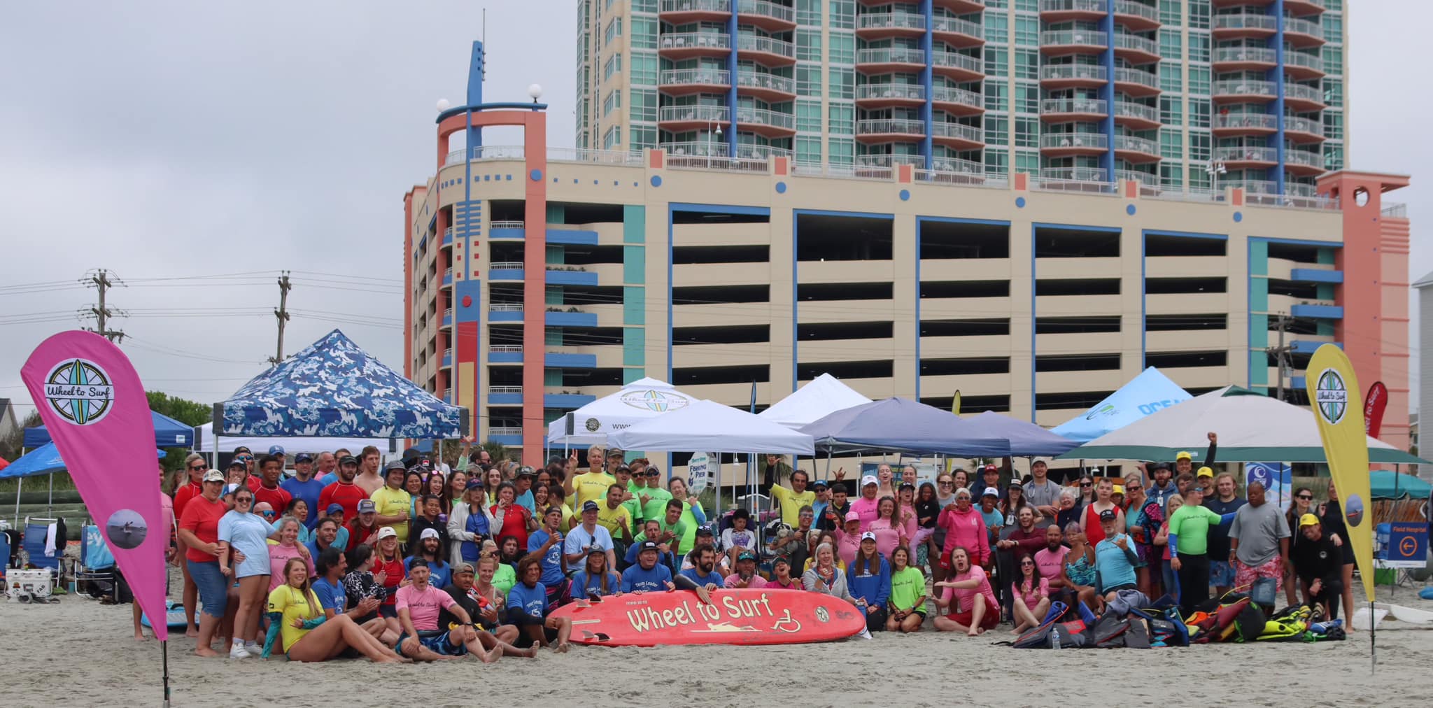 A group picture on the beach of a Wheel to Surf event